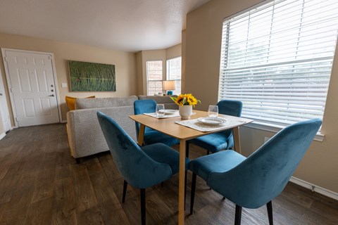 A dining room with a table set for two and blue chairs.