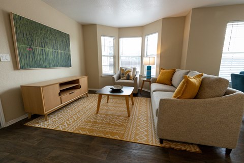A living room with a brown rug and a painting on the wall.