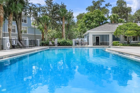 A swimming pool surrounded by palm trees and a building.