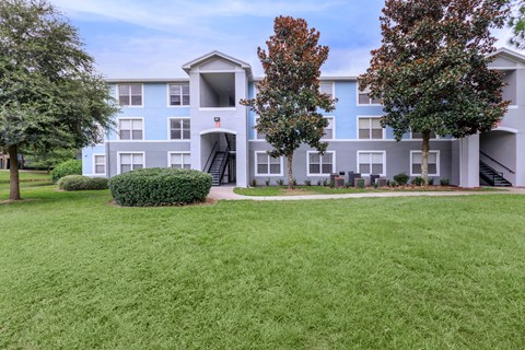 A large grassy area in front of a multi-story apartment building.