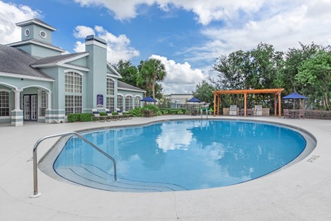 A large swimming pool in front of a building with a gazebo.