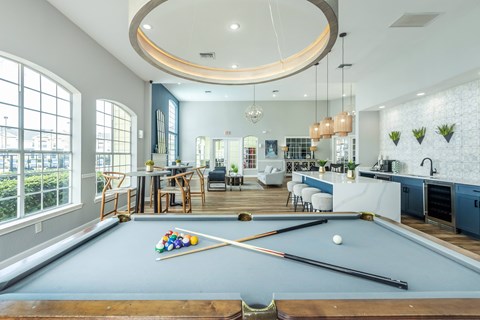 A pool table is in the middle of a room with a kitchen and dining area.