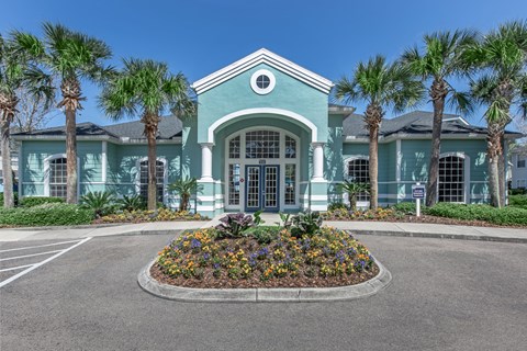A building with a greenish hue and a circular flower bed in front.