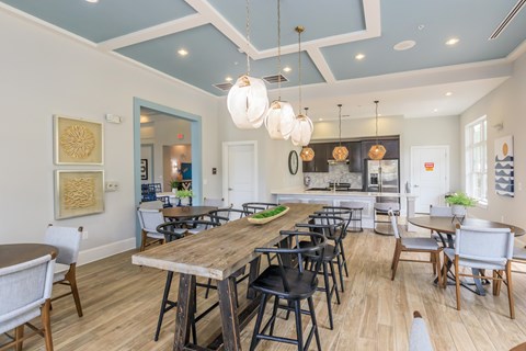 A dining room with a long wooden table surrounded by chairs.