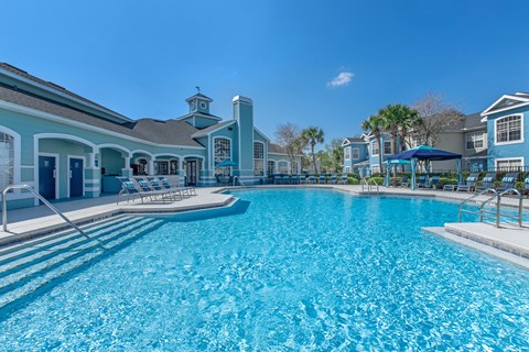 A large swimming pool in front of a building with a clock tower.