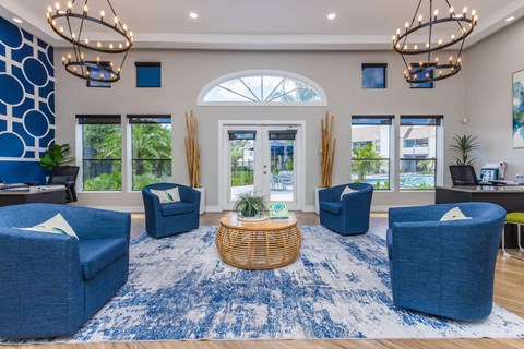 A spacious living room with blue chairs and a woven basket on the rug.