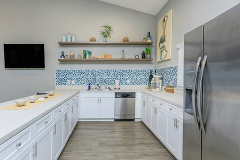 A kitchen with white cabinets and a blue tile backsplash.