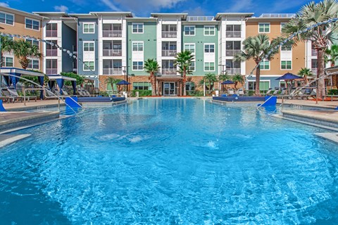 A large swimming pool in front of a multi-story apartment building.