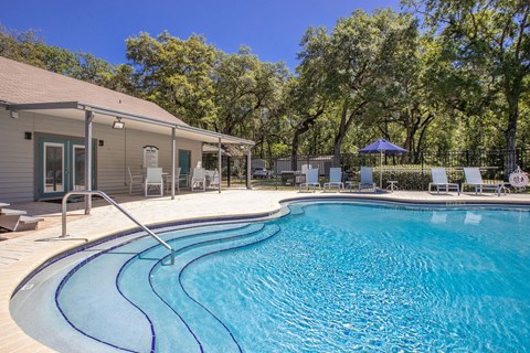 A swimming pool with a slide and a house in the background.