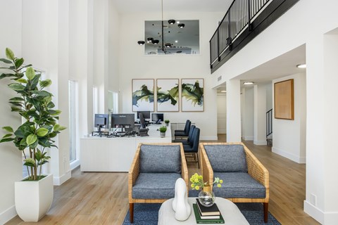 A living room with a grey couch and a white vase.
