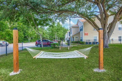 A hammock is strung between two wooden posts in a grassy area.