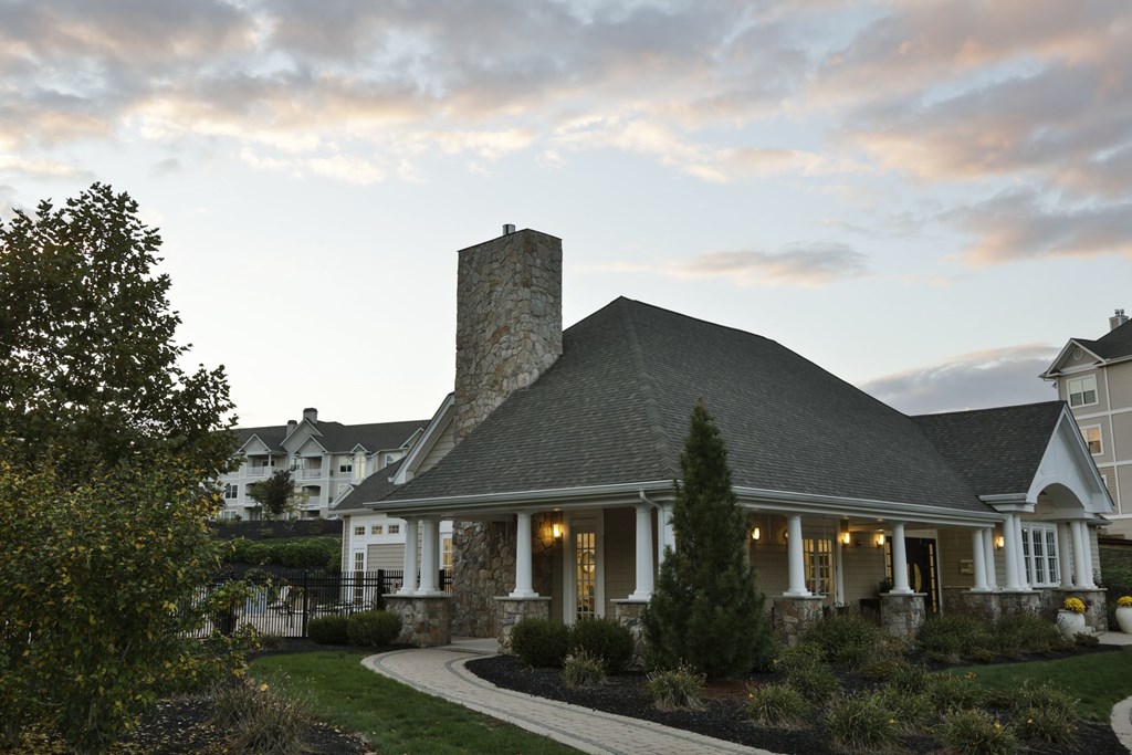 A house with a stone chimney is surrounded by a garden.