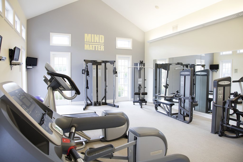 A gym with a row of treadmills and a wall that says Mind Matter.