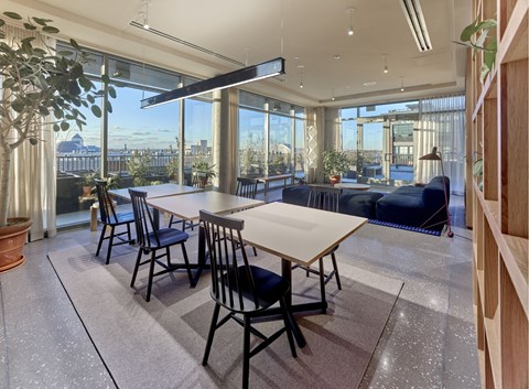 A dining room with a table and chairs with a view of the city.
