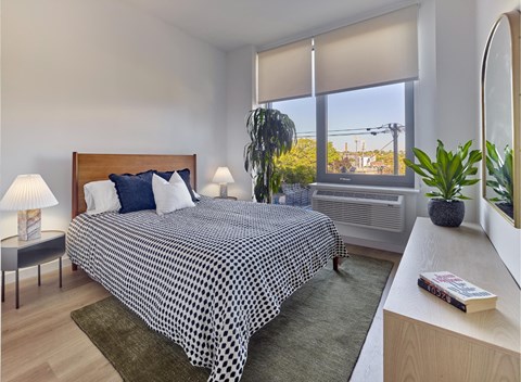 A bedroom with a large bed and a window with blinds.