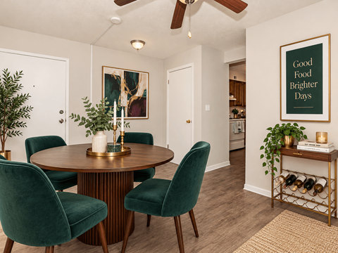 A dining room with a round table and green chairs.