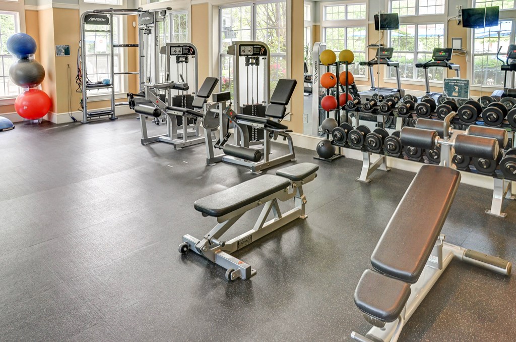 a gym with weights and cardio equipment in a building with windows