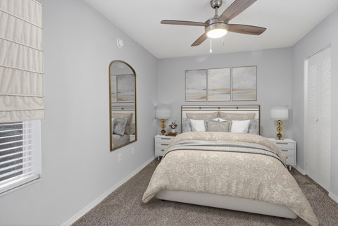 A bedroom with a large bed and a ceiling fan.