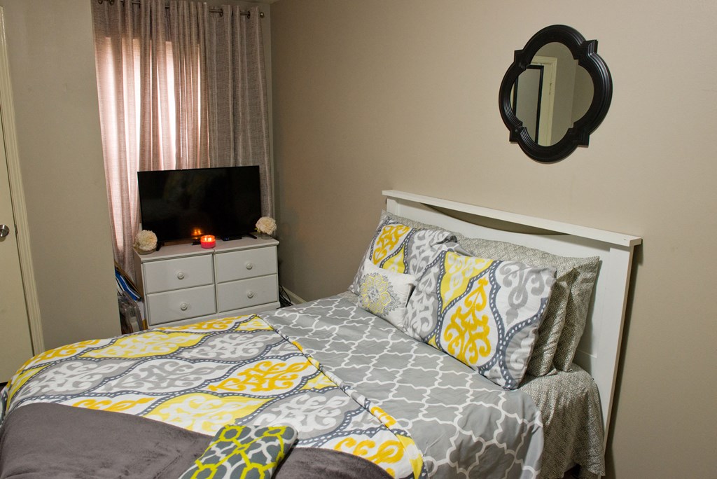 a bedroom with a bed and a dresser and a mirror