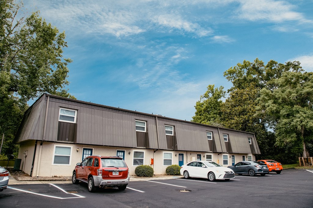 an apartment building with cars parked in a parking lot