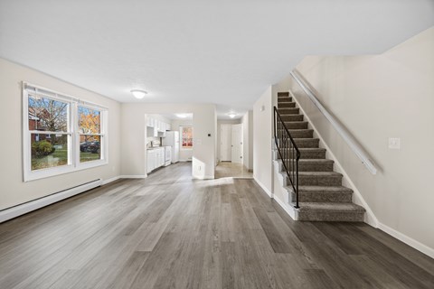 A spacious room with a staircase and a view of the outdoors through a window.