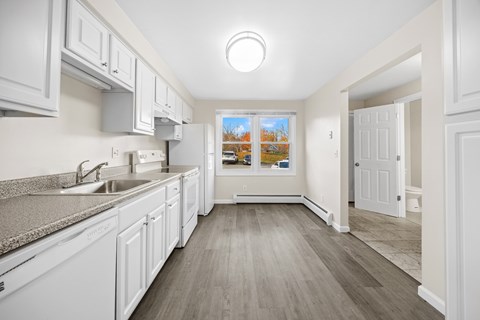 A kitchen with white cabinets and a grey counter top.
