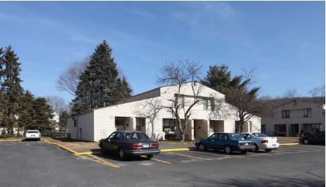 A white building with a parking lot in front of it.