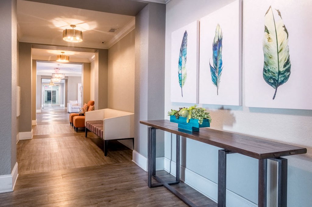 a long hallway with paintings on the wall and a table with plants at Linden on the GreeneWay, Orlando, 32824
