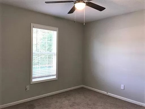 an empty room with a window and a ceiling fan