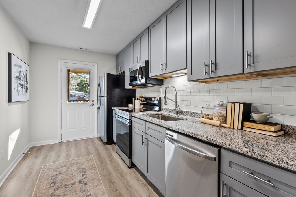 A kitchen with a black fridge and stainless steel dishwasher at West Oak Apartments, North Carolina 27587