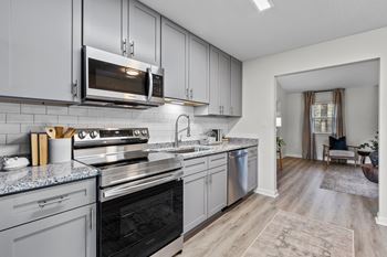 A modern kitchen with a black oven and grey cabinets at West Oak Apartments, Wake Forest, NC