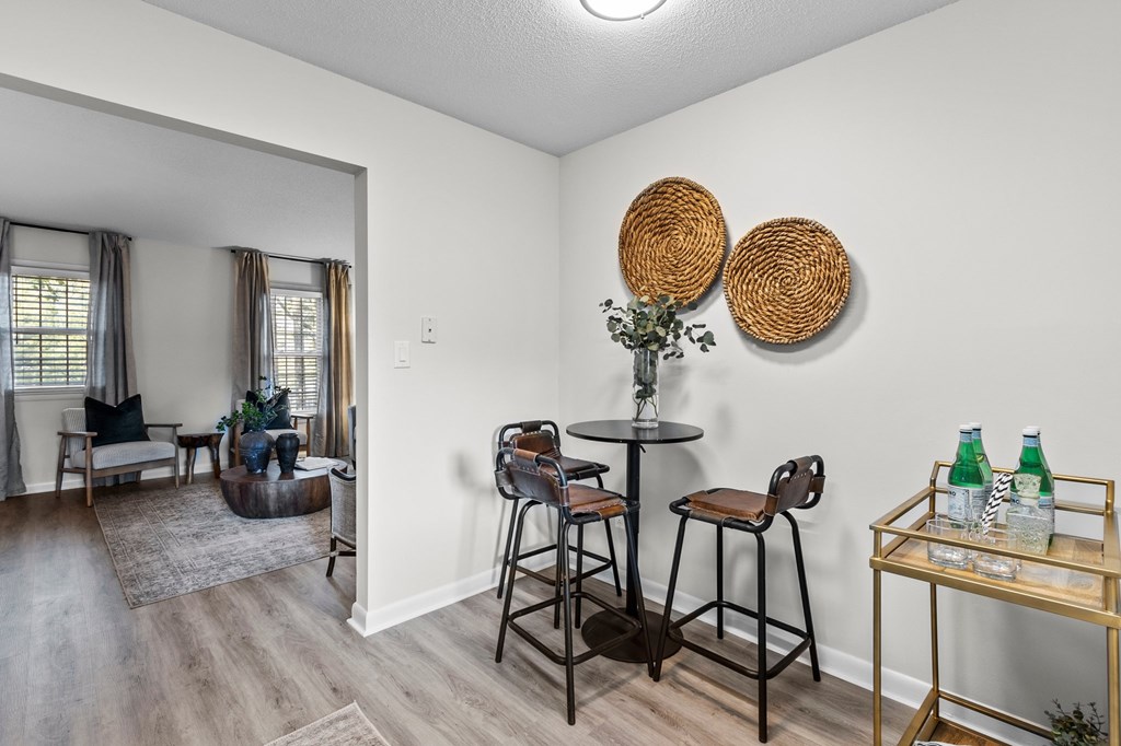 A living room with a bar stool and a table at West Oak Apartments, Wake Forest, NC