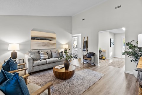 A living room with a grey couch, a wooden coffee table, and a large painting on the wall.