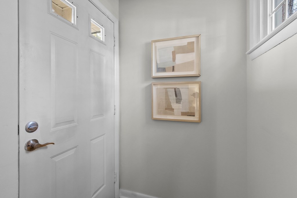 A white door with a silver handle and a picture frame on the wall at West Oak Apartments, Wake Forest, North Carolina