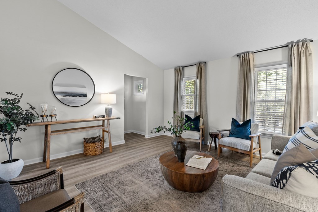 A living room with a grey couch, a wooden coffee table, and a mirror on the wall at West Oak Apartments, North Carolina