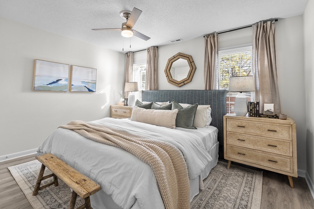A bedroom with a bed, a bench, a dresser, and a ceiling fan at West Oak Apartments, Wake Forest, North Carolina