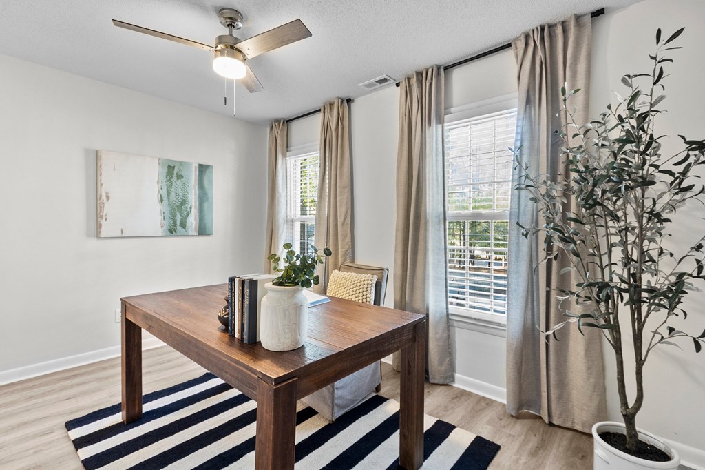 A room with a table, a plant, and a painting on the wall at West Oak Apartments, Wake Forest, North Carolina