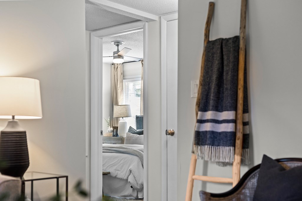 A bedroom with a bed, a lamp, and a blanket on a ladder at West Oak Apartments, Wake Forest