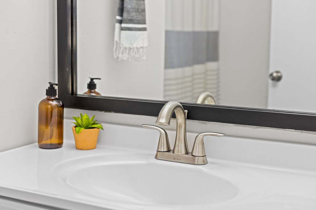 A bathroom sink with a silver faucet and two soap dispensers at West Oak Apartments, North Carolina