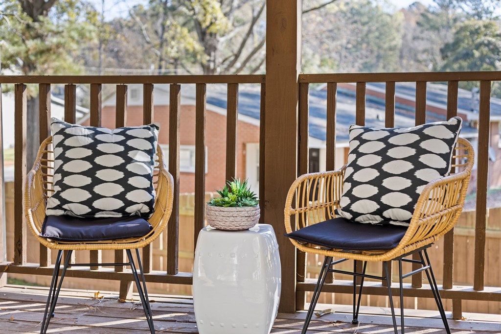 Two chairs with black and white pillows on a wooden balcony at West Oak Apartments, North Carolina