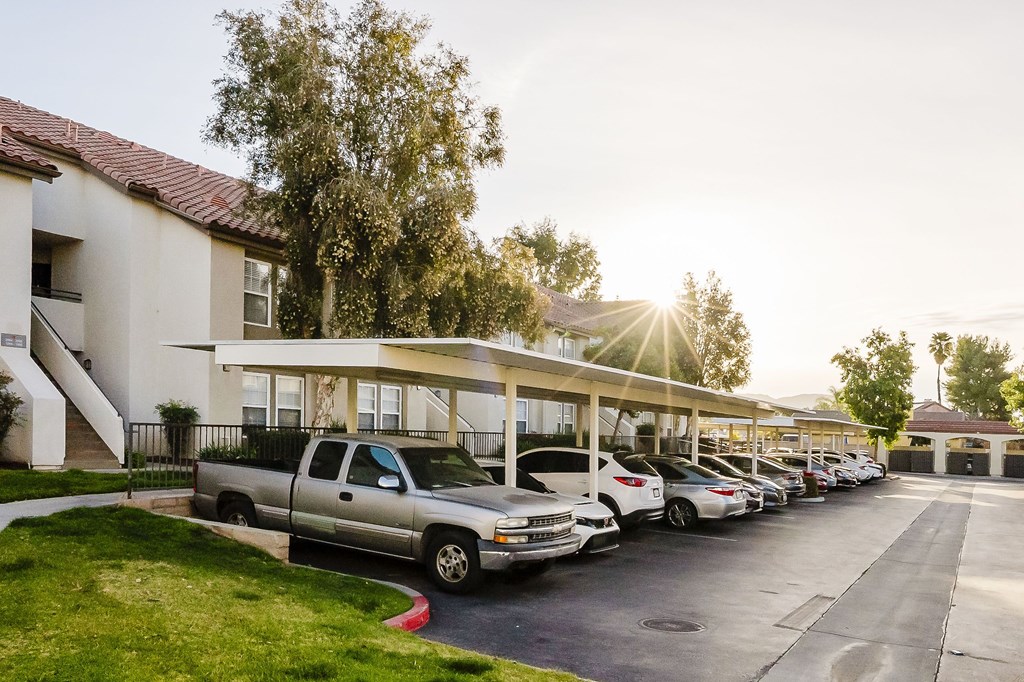 A parking lot with cars parked in front of a building with a tree in the background. at Legends at Rancho Belago, Moreno Valley, CA, 92553