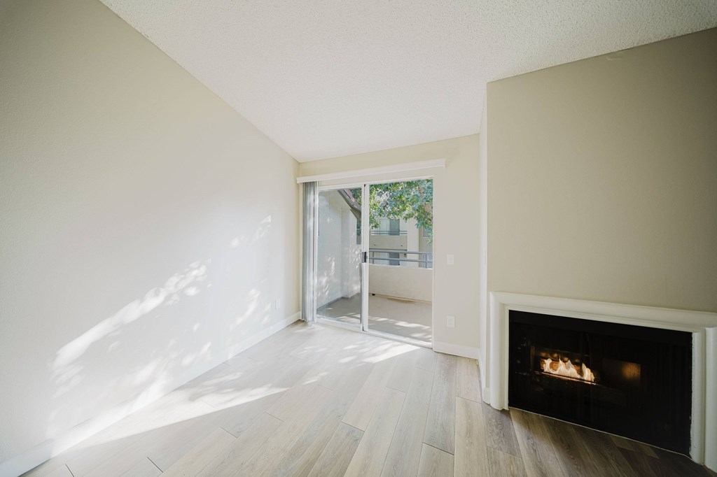 A room with a fireplace and a view of a tree-lined street through a glass door. at Legends at Rancho Belago, Moreno Valley, California