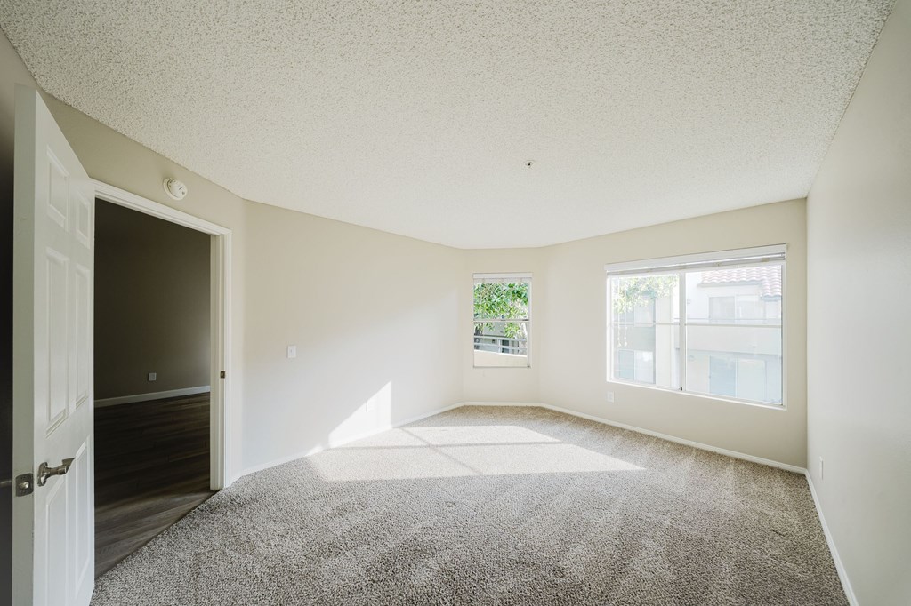 A room with a carpeted floor and a door leading to another room. at Legends at Rancho Belago, California