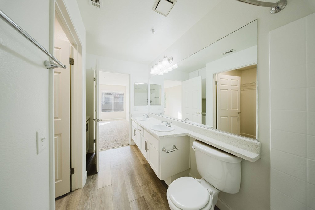 A white bathroom with a toilet, sink and mirror. at Legends at Rancho Belago, Moreno Valley, 92553