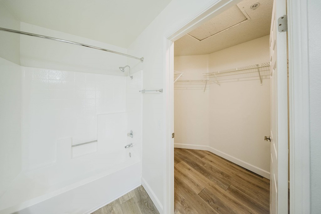 A white bathroom with a walk-in shower and a wooden floor. at Legends at Rancho Belago, Moreno Valley, California