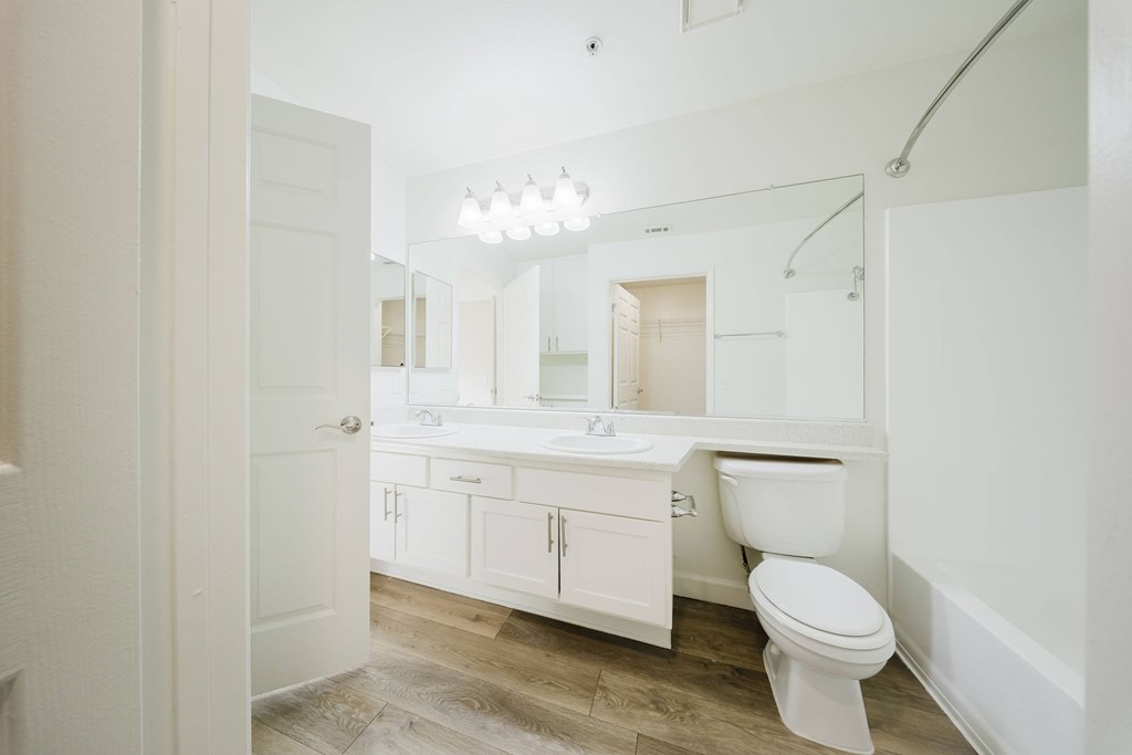 A white bathroom with a toilet, sink, and mirror. at Legends at Rancho Belago, Moreno Valley