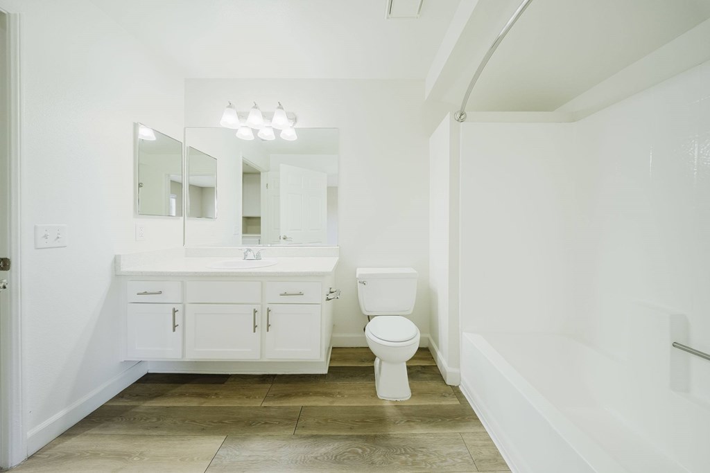 A white bathroom with a toilet, sink, and mirror. at Legends at Rancho Belago, Moreno Valley, CA