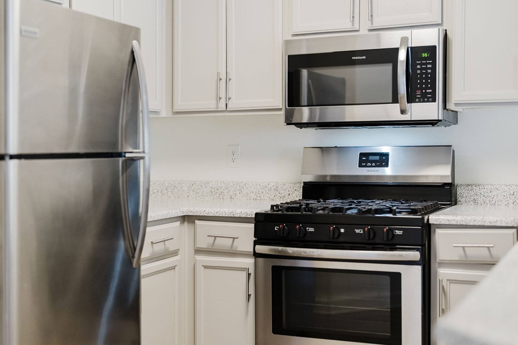 A modern kitchen with a stainless steel refrigerator, microwave, and stove. at Legends at Rancho Belago, Moreno Valley, CA