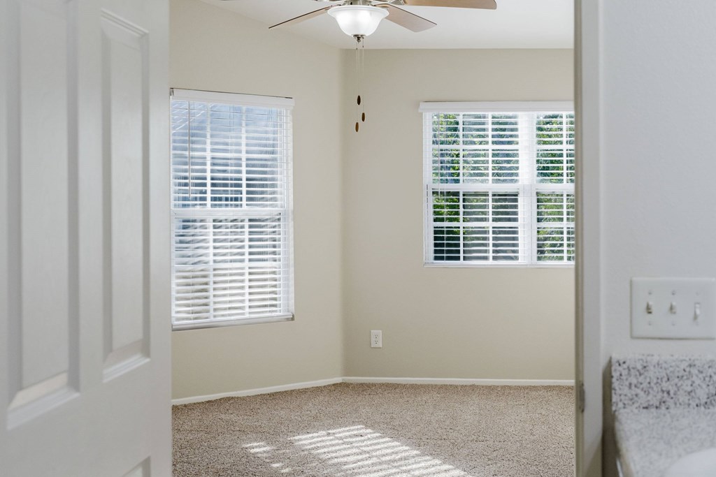 A room with a ceiling fan and two windows with blinds. at Legends at Rancho Belago, Moreno Valley, California