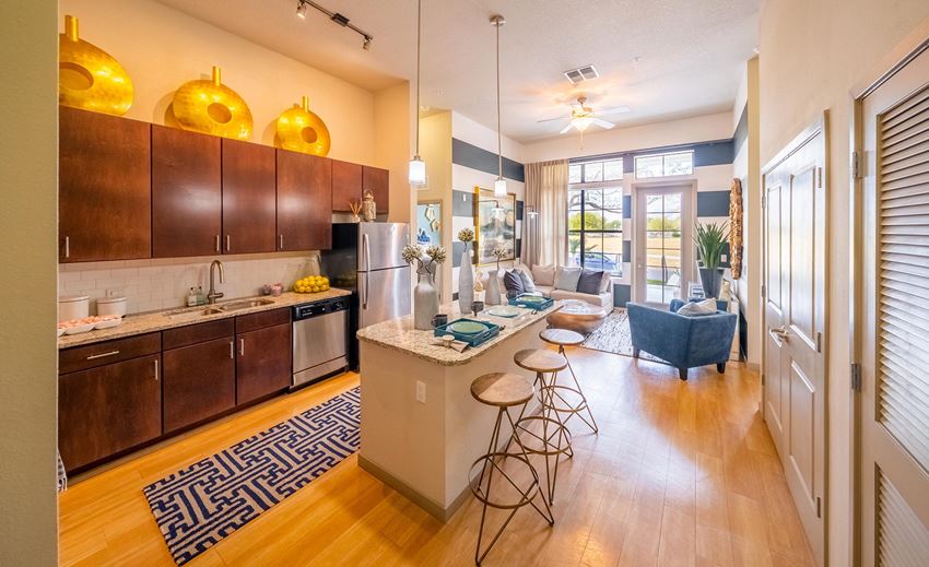 a living room with a kitchen and a bar with stools